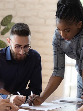 Diverse group of people at an office meeting looking at paper on table